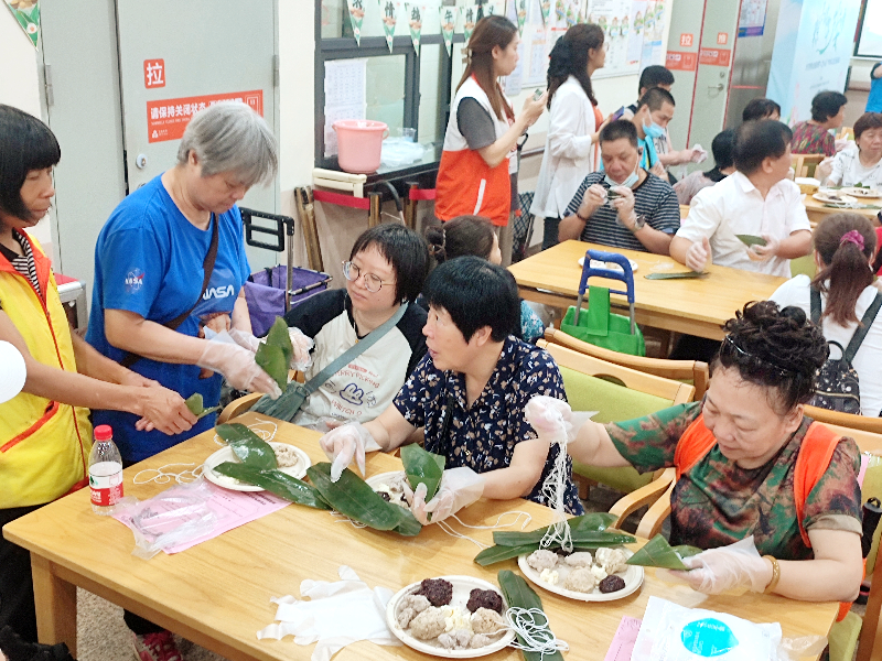 图：志愿者给居民们示范如何包燕麦紫米粽子.jpg