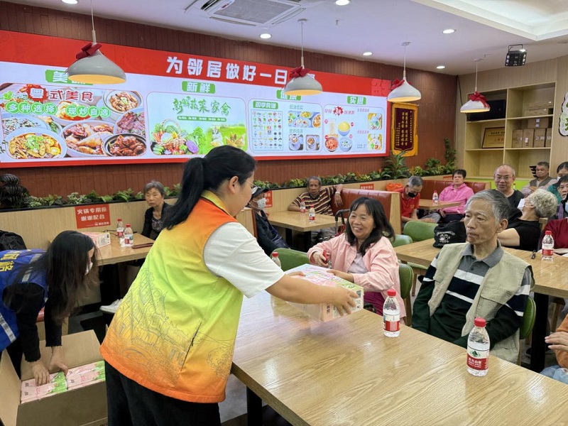 图：社区工作者为居民派发活动纪念品.jpg