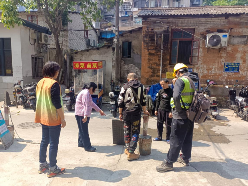 （图：维修人员与网格员、居民共同商讨疏通方案）.png